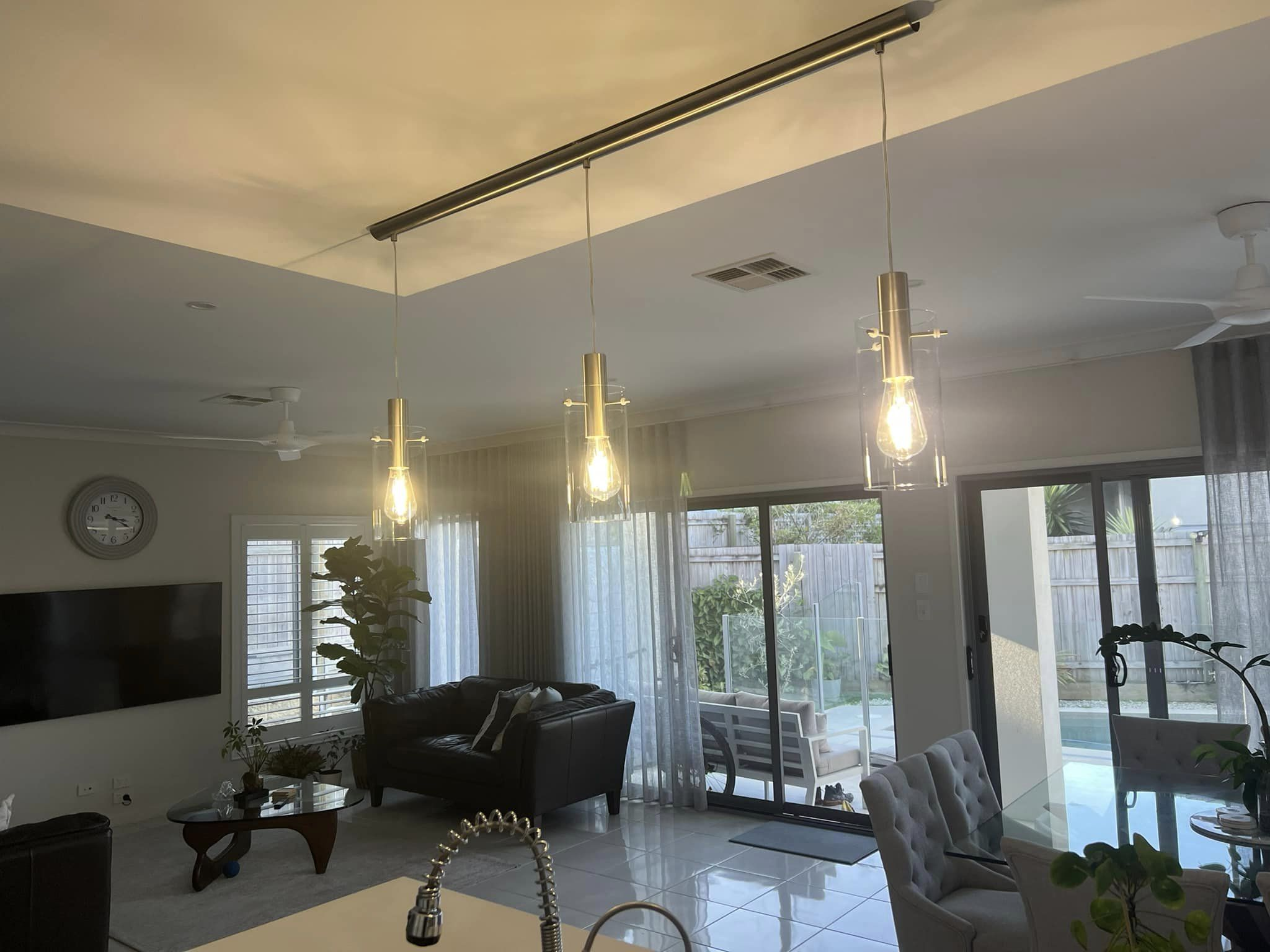 Living room and dining area with hanging lights and glass doors to pool.